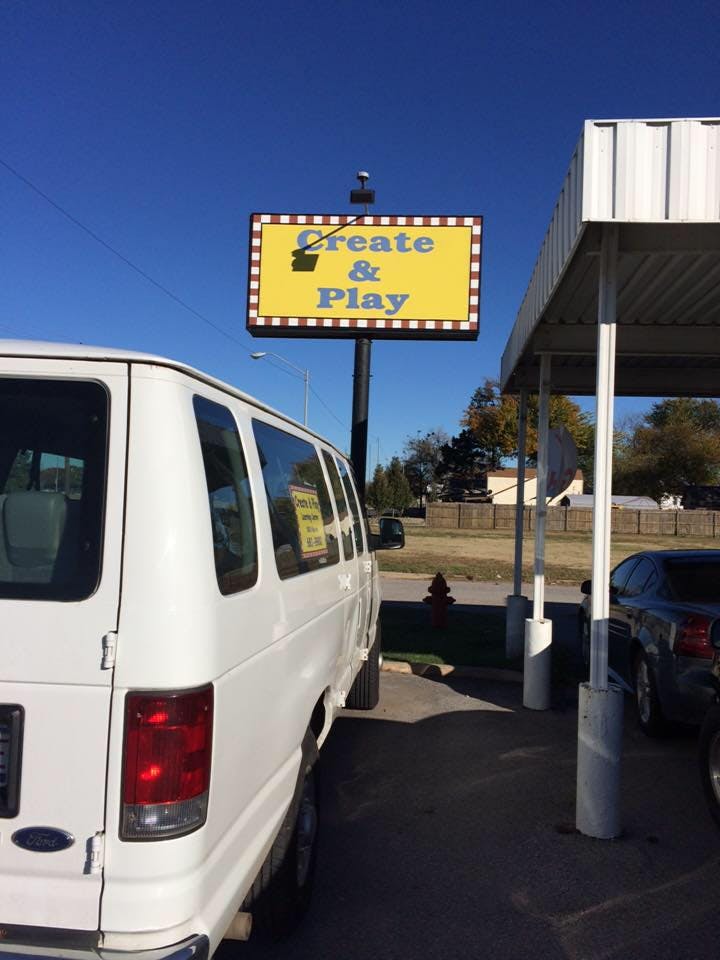 White van parked next to a sign that reads "Create & Play"