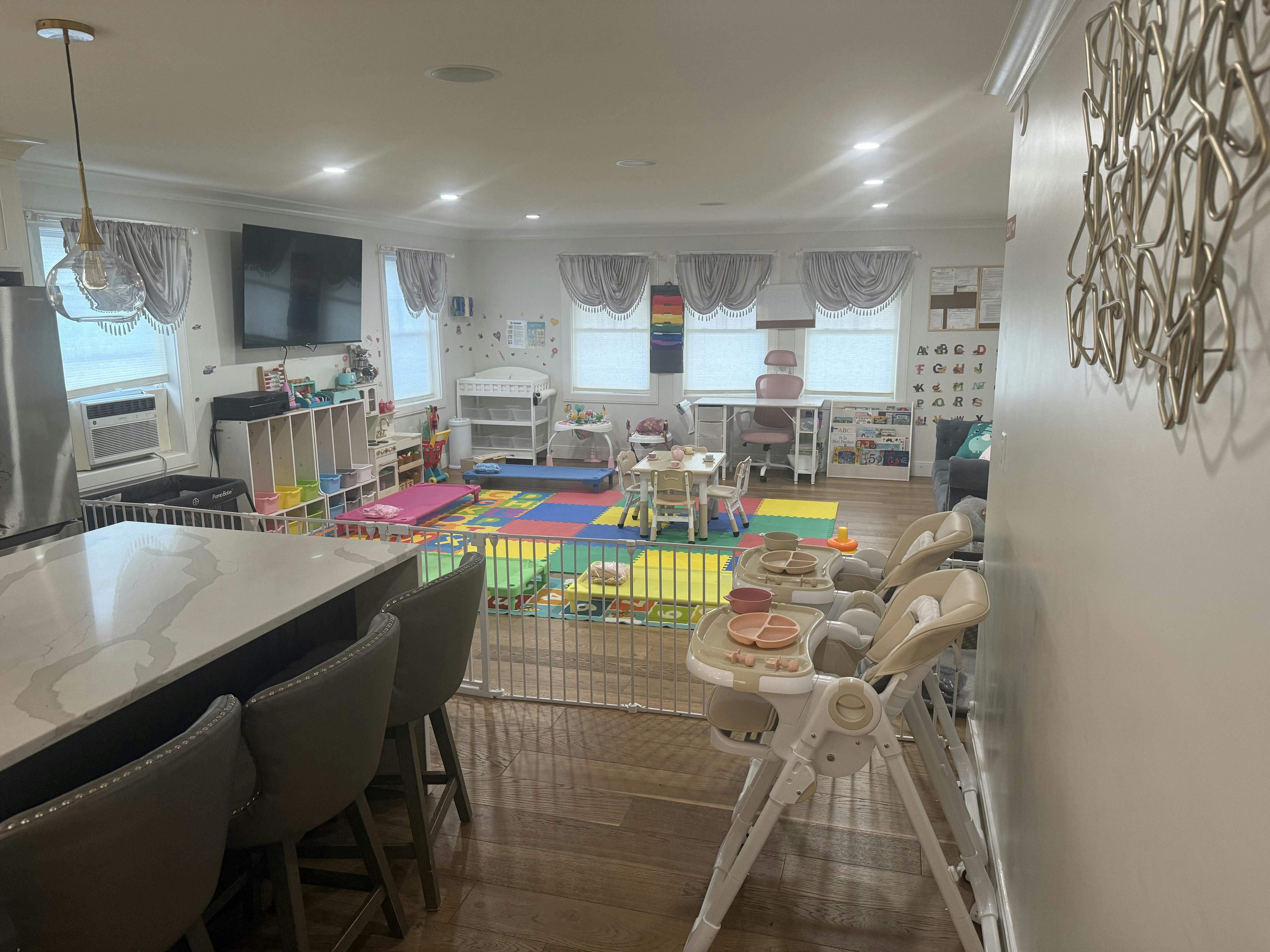 Children's play area with colorful mats, baby gates, high chairs, and small furniture