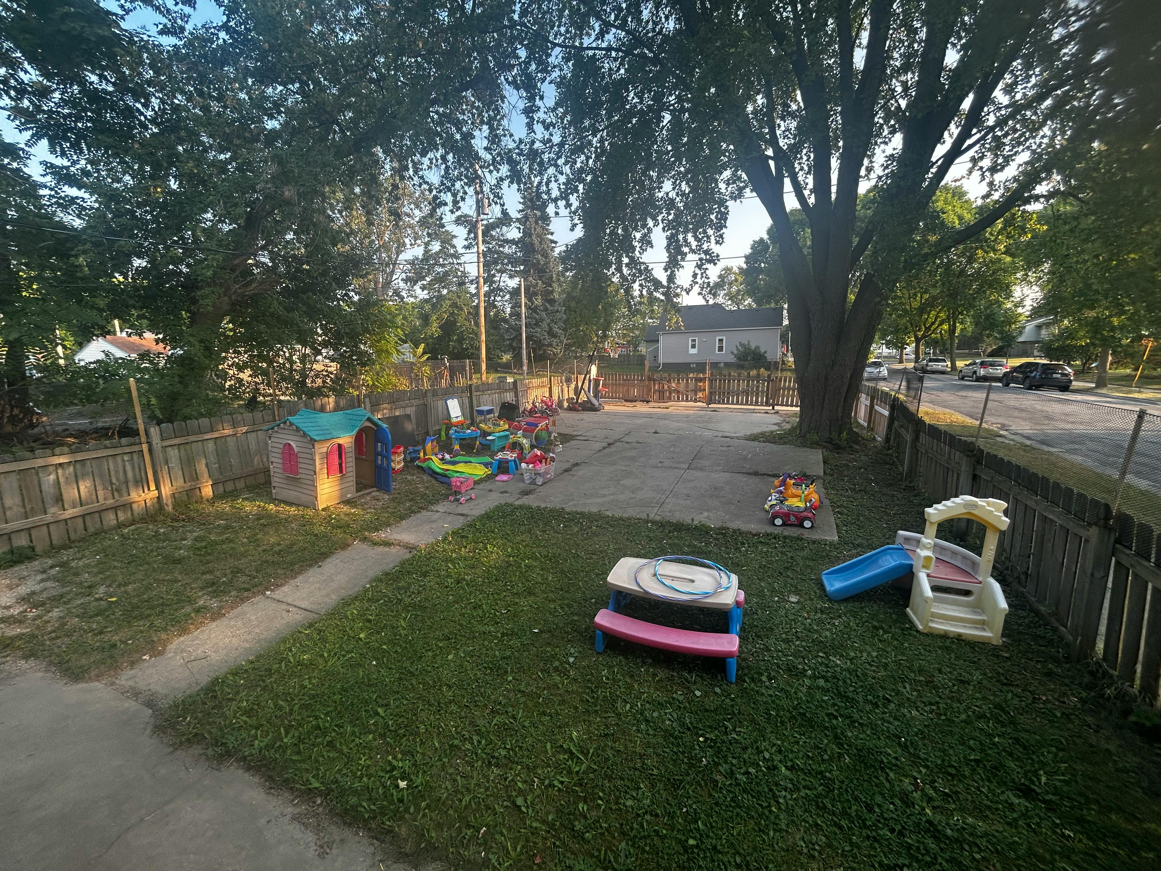 Outdoor play area with small slide, playhouse, and toys