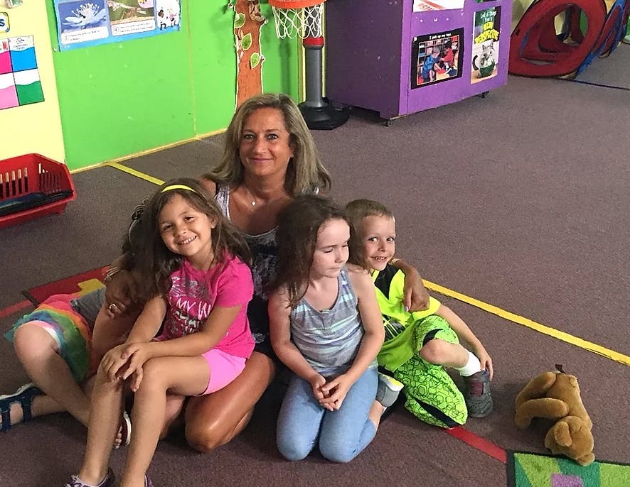 Adult and three children sitting on the floor in a classroom