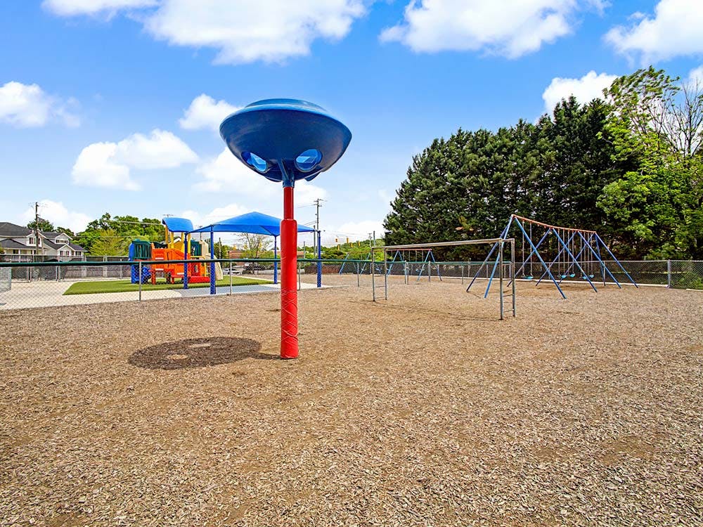 Playground with swings, play structure, and blue shade covering wood chips
