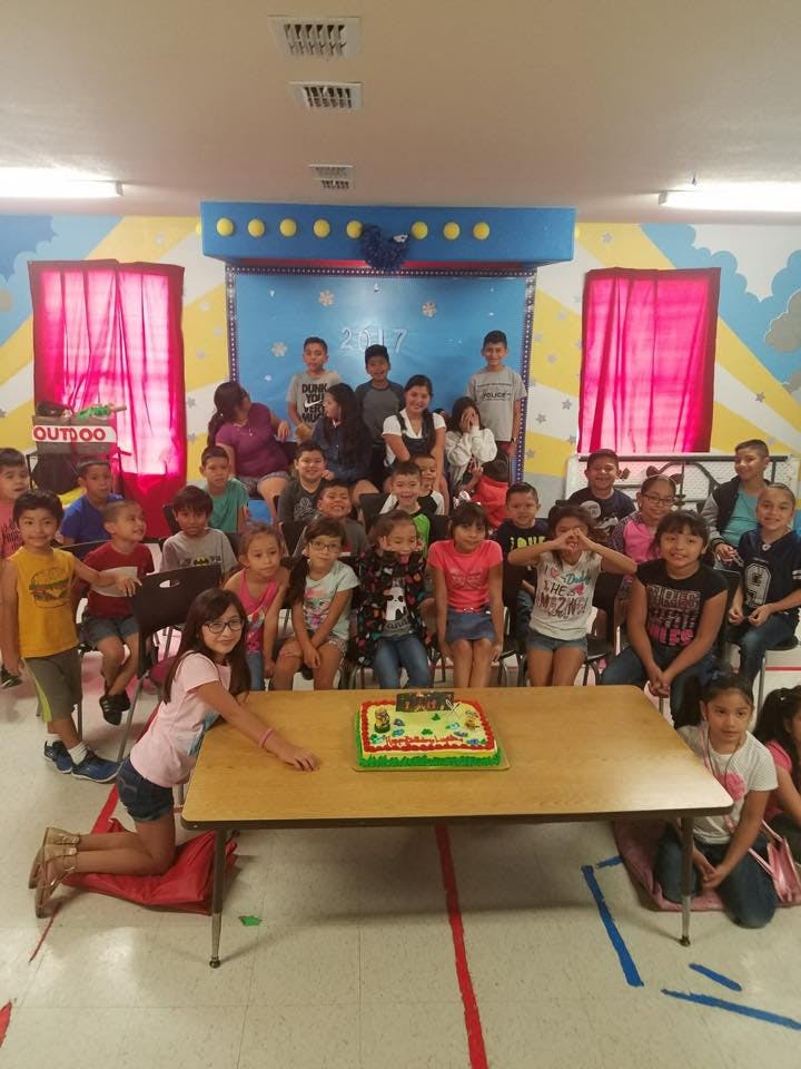 Group of children and adults posing with a cake on a table