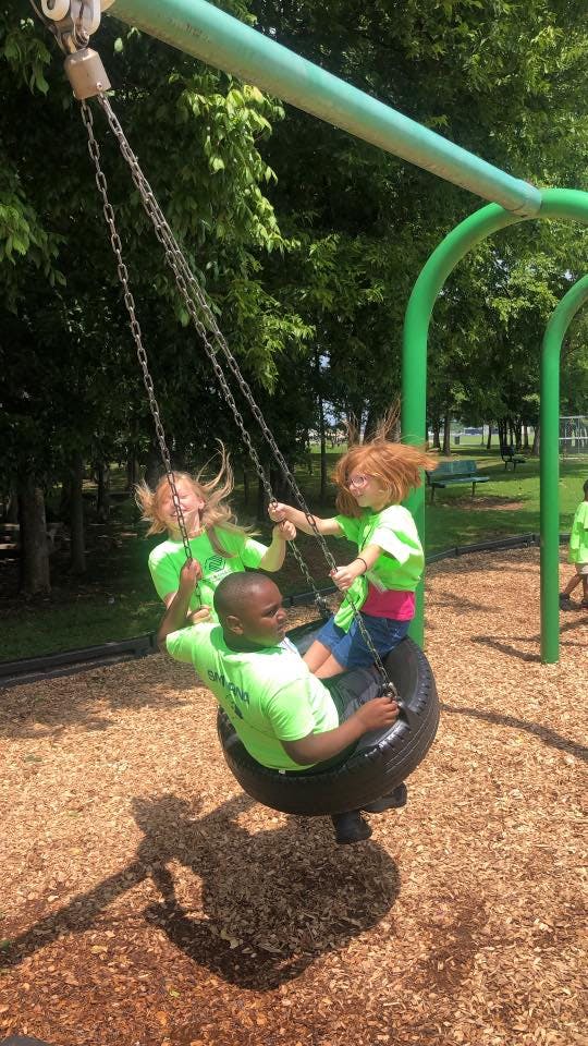 Three children on a tire swing at a playground