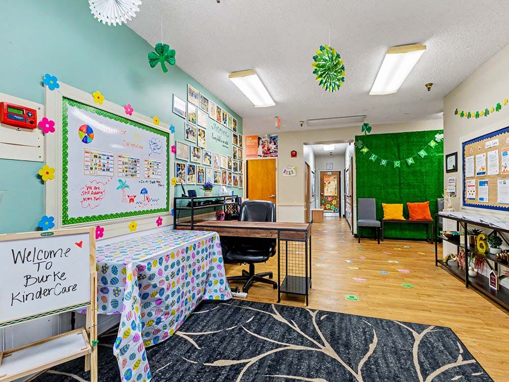 An empty decorated classroom with a whiteboard, desk, and hallway