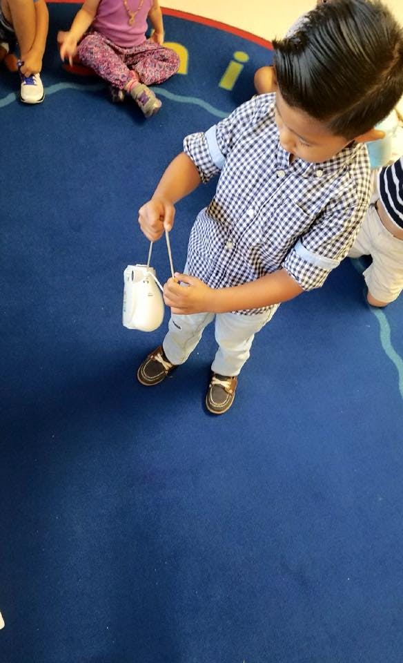 Child holding a white object with strings in a classroom