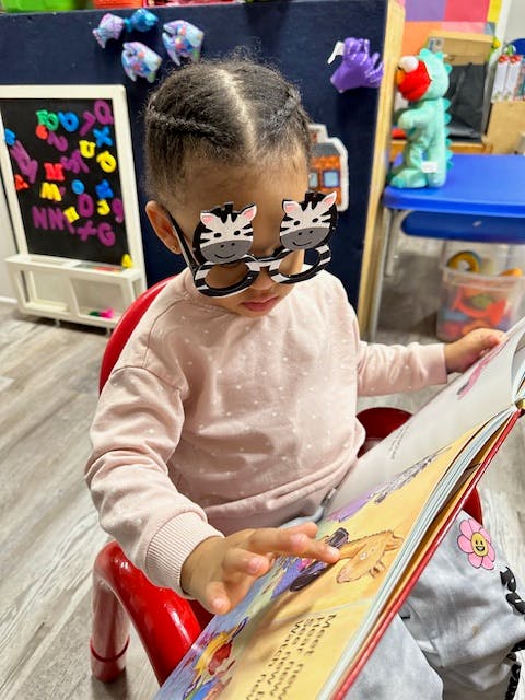 Child wearing zebra glasses reading a book