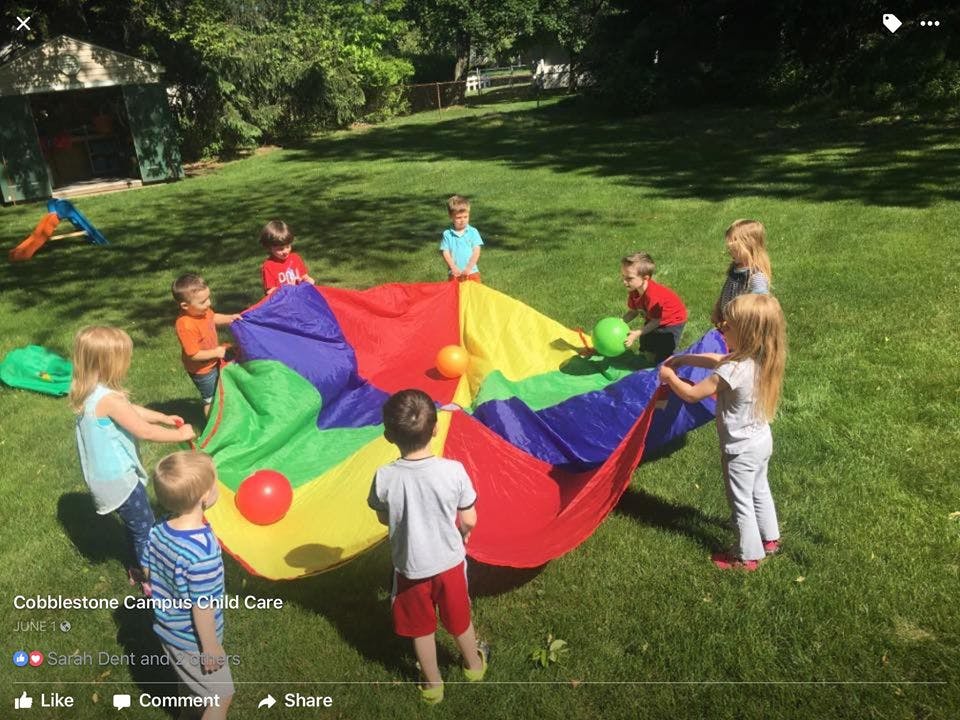 Children playing with a colorful parachute on a grassy lawn