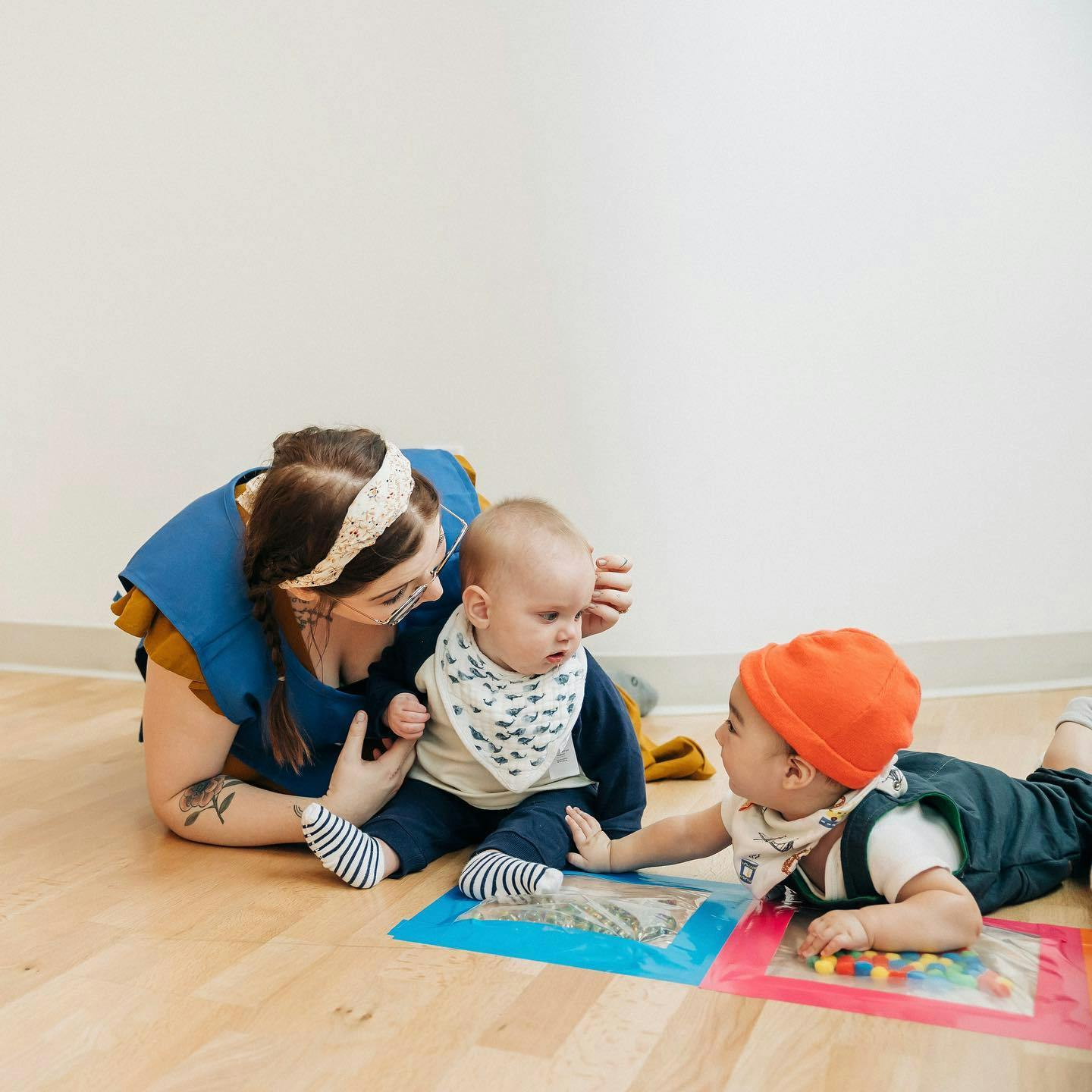 Person with two children playing on the floor with sensory mats