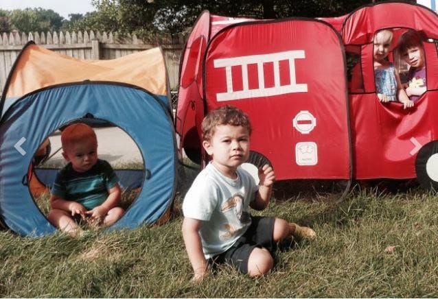 Children playing with pop-up tents in a yard