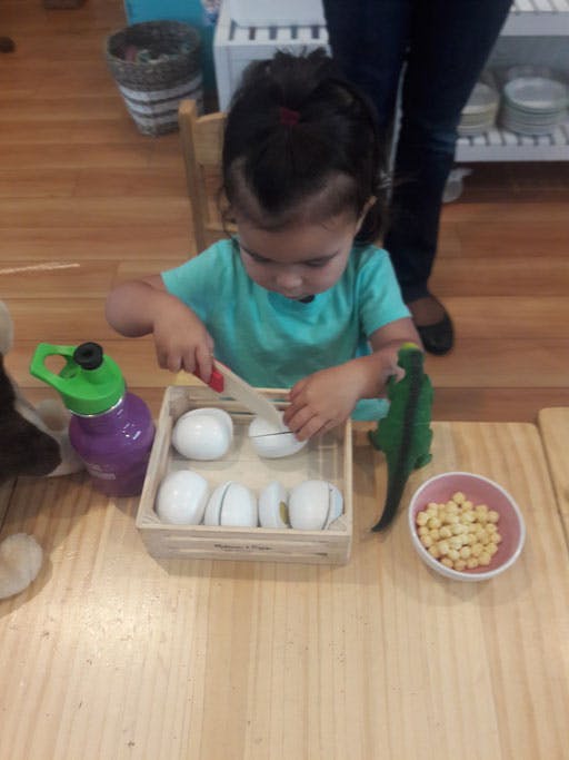 Child playing with toy food and knife at a table