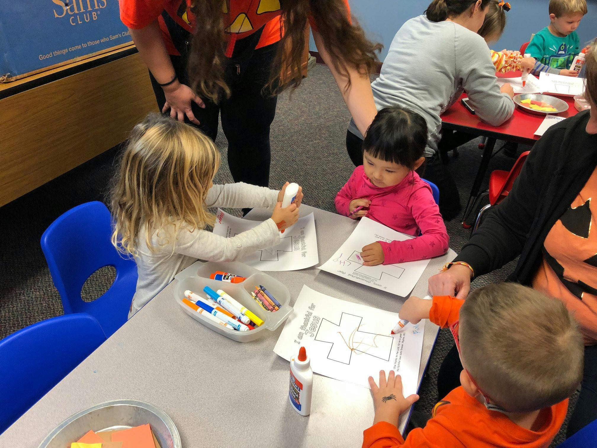 Children at a table doing an activity with paper and glue