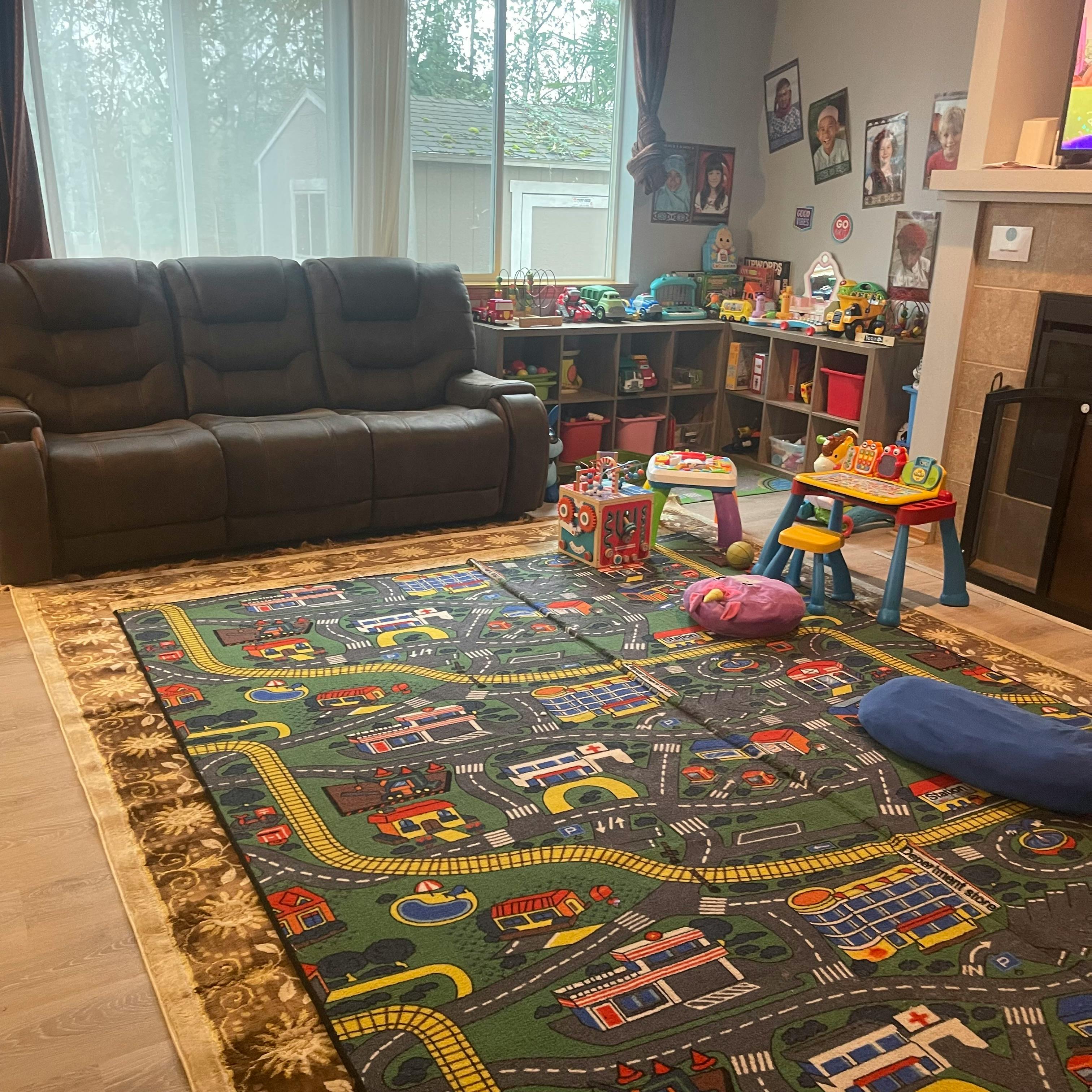 Living room with a large playmat, sofa, and toy shelves