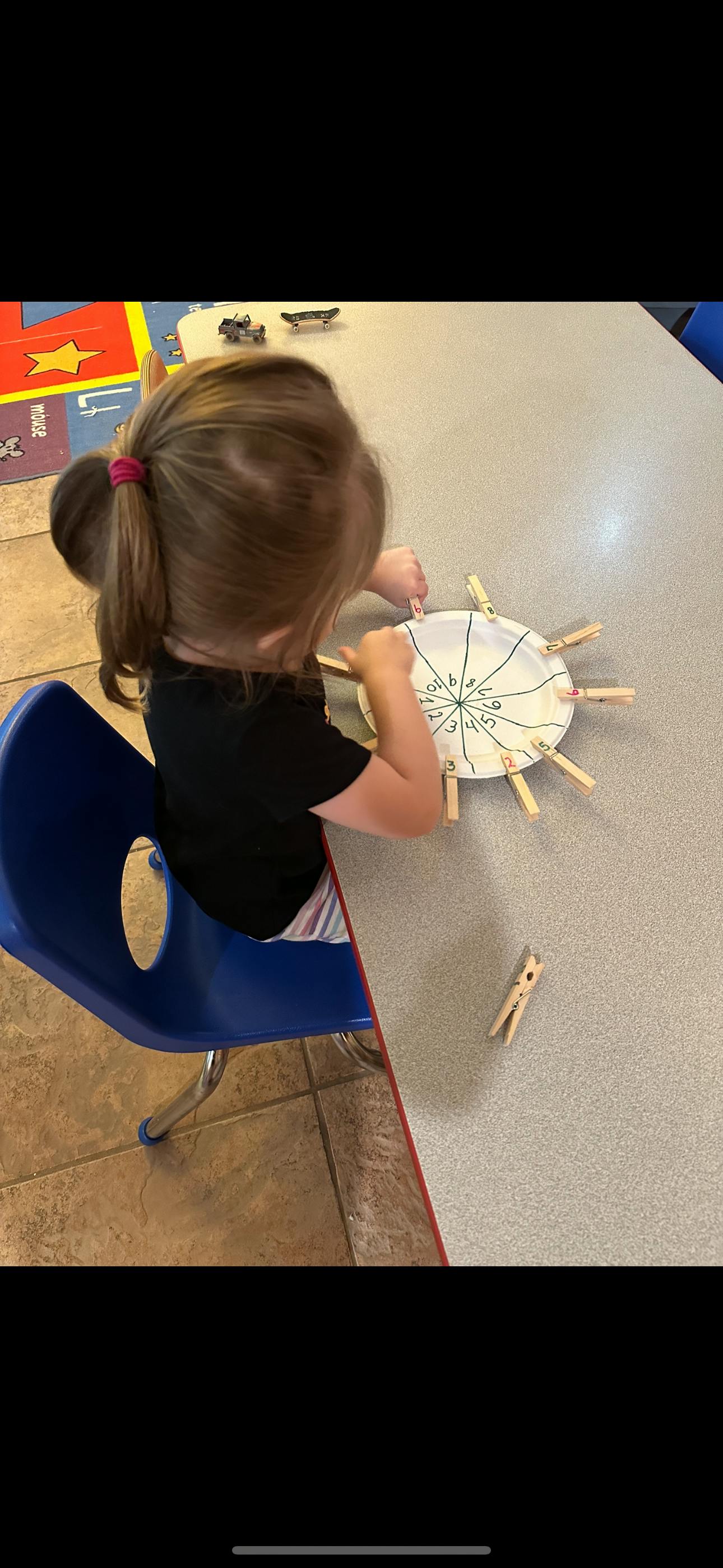 Child playing with a paper plate and clothespins