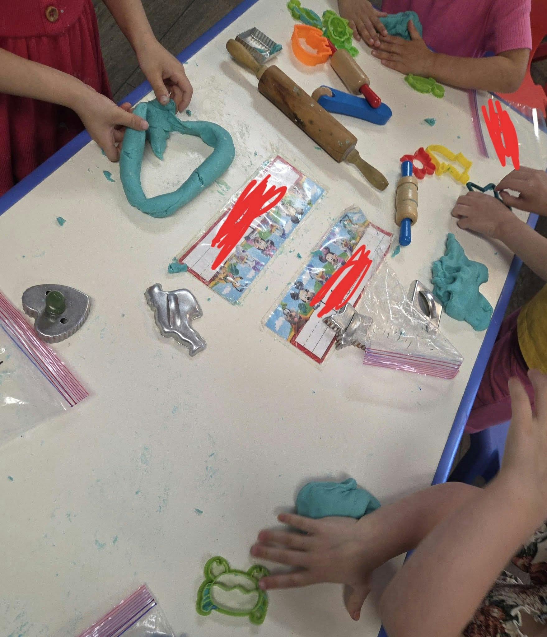 Children playing with blue playdough and cookie cutters at a table
