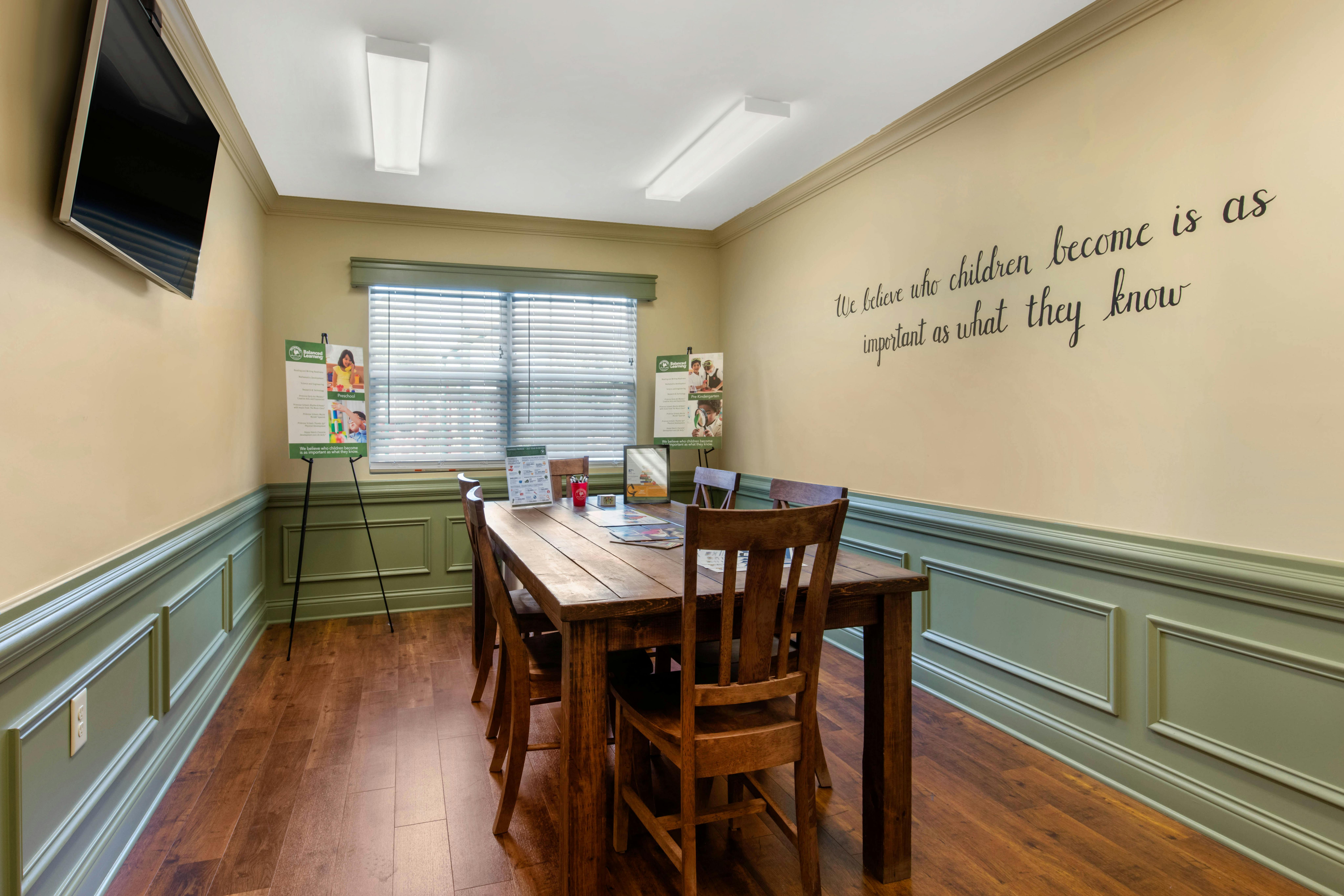 Room with wood paneling, a large table and chairs, and signs on easels
