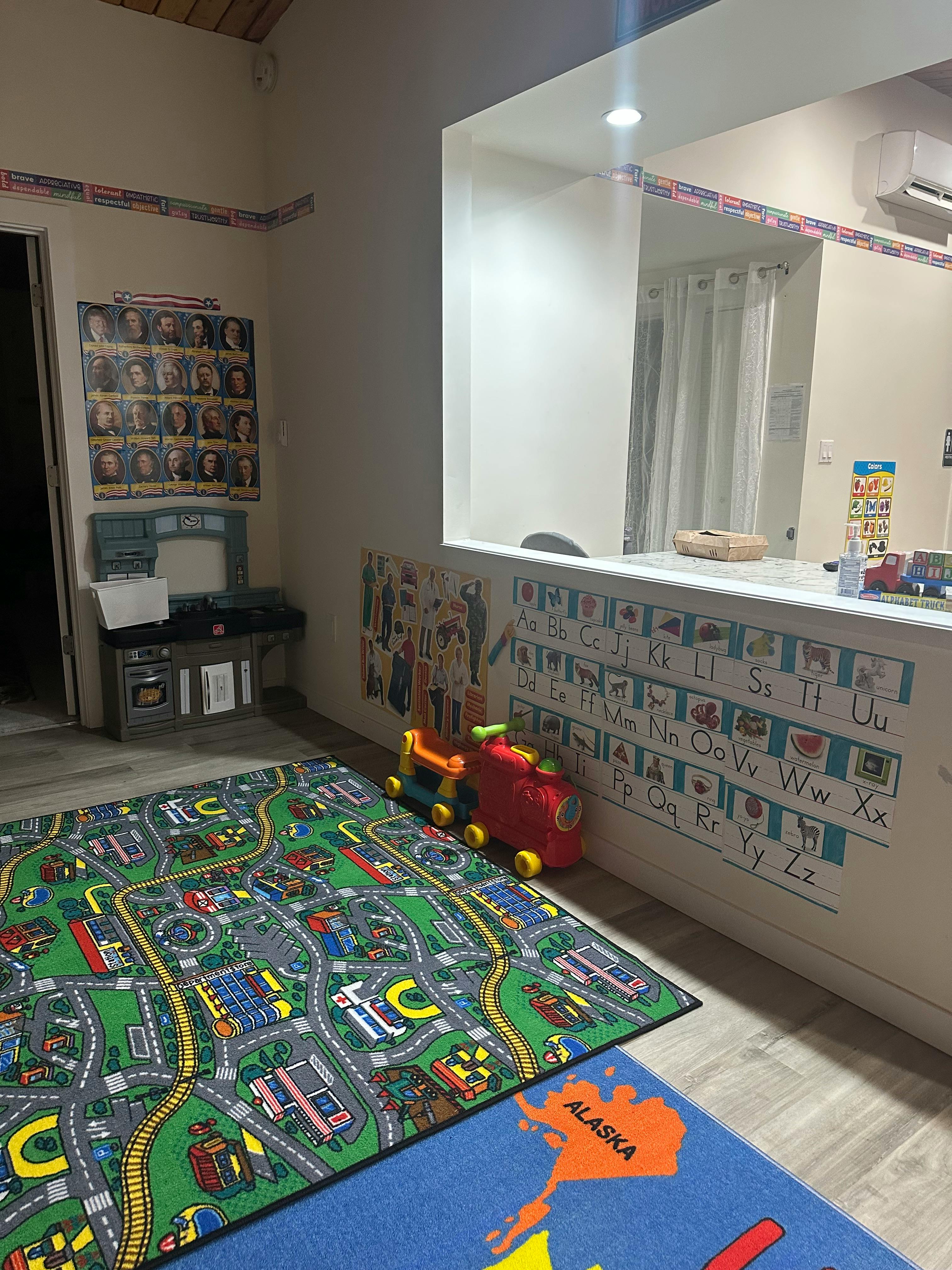 Playroom with a road map rug, toy train, and alphabet chart on the wall