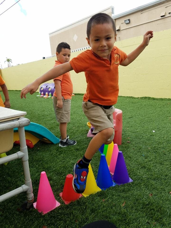 Child balancing on colorful cones on artificial grass