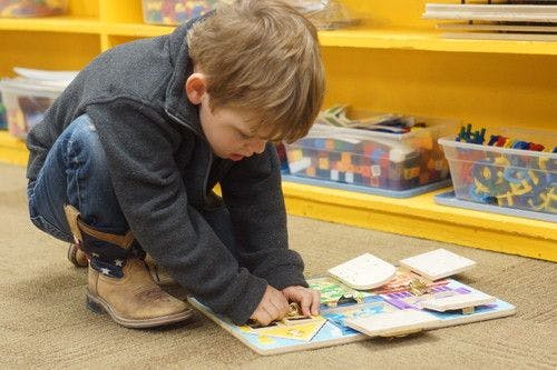 Child playing with a puzzle on the floor