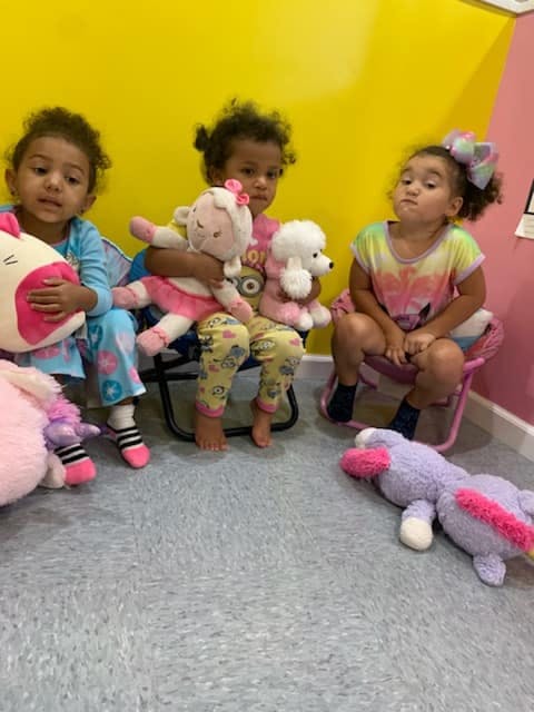 Three children sitting with stuffed animals