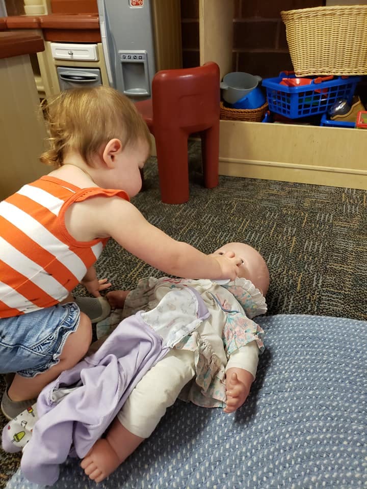 Child playing with a doll on the floor