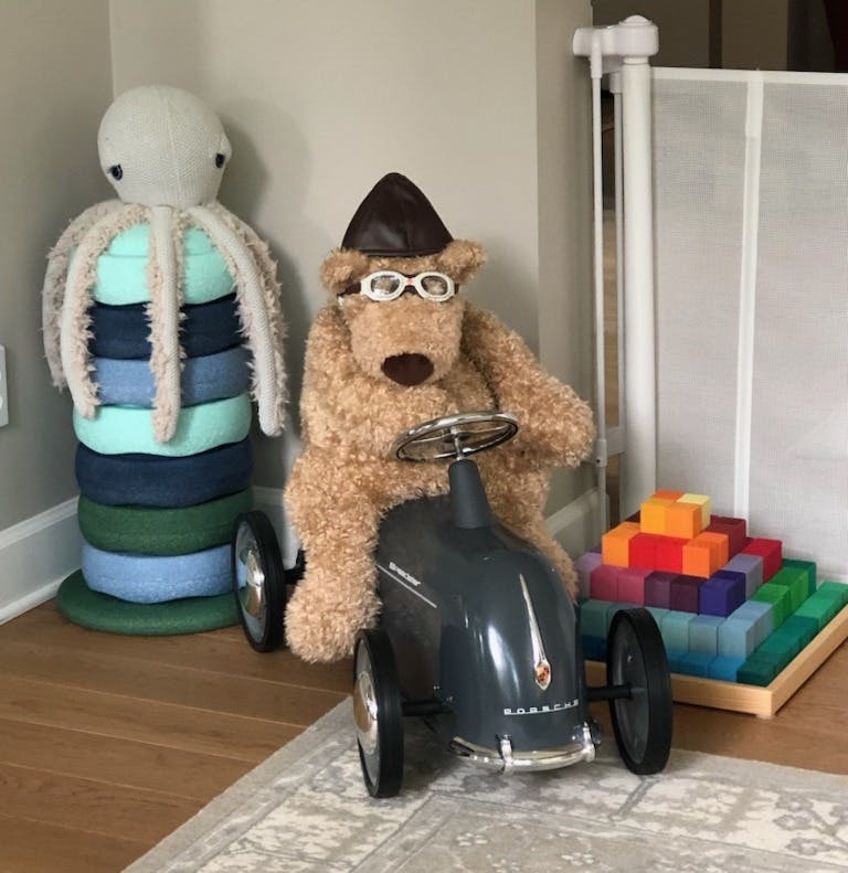 Stuffed bear in a hat and goggles sitting in a toy car next to a stuffed octopus