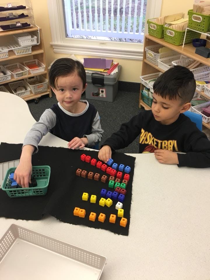 Two children playing with colorful interlocking blocks on a black mat