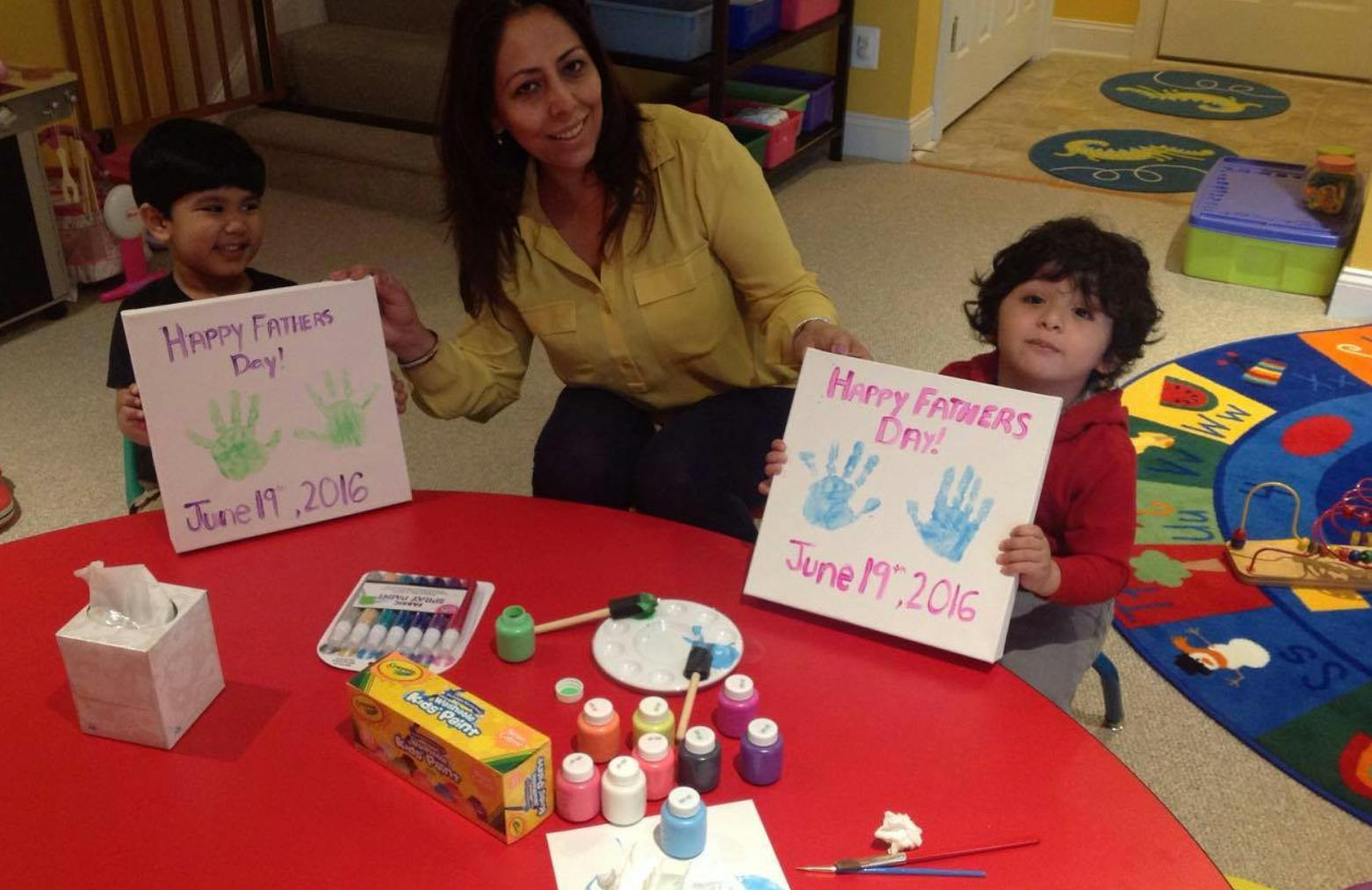 Adult and two children holding up handmade signs with handprints
