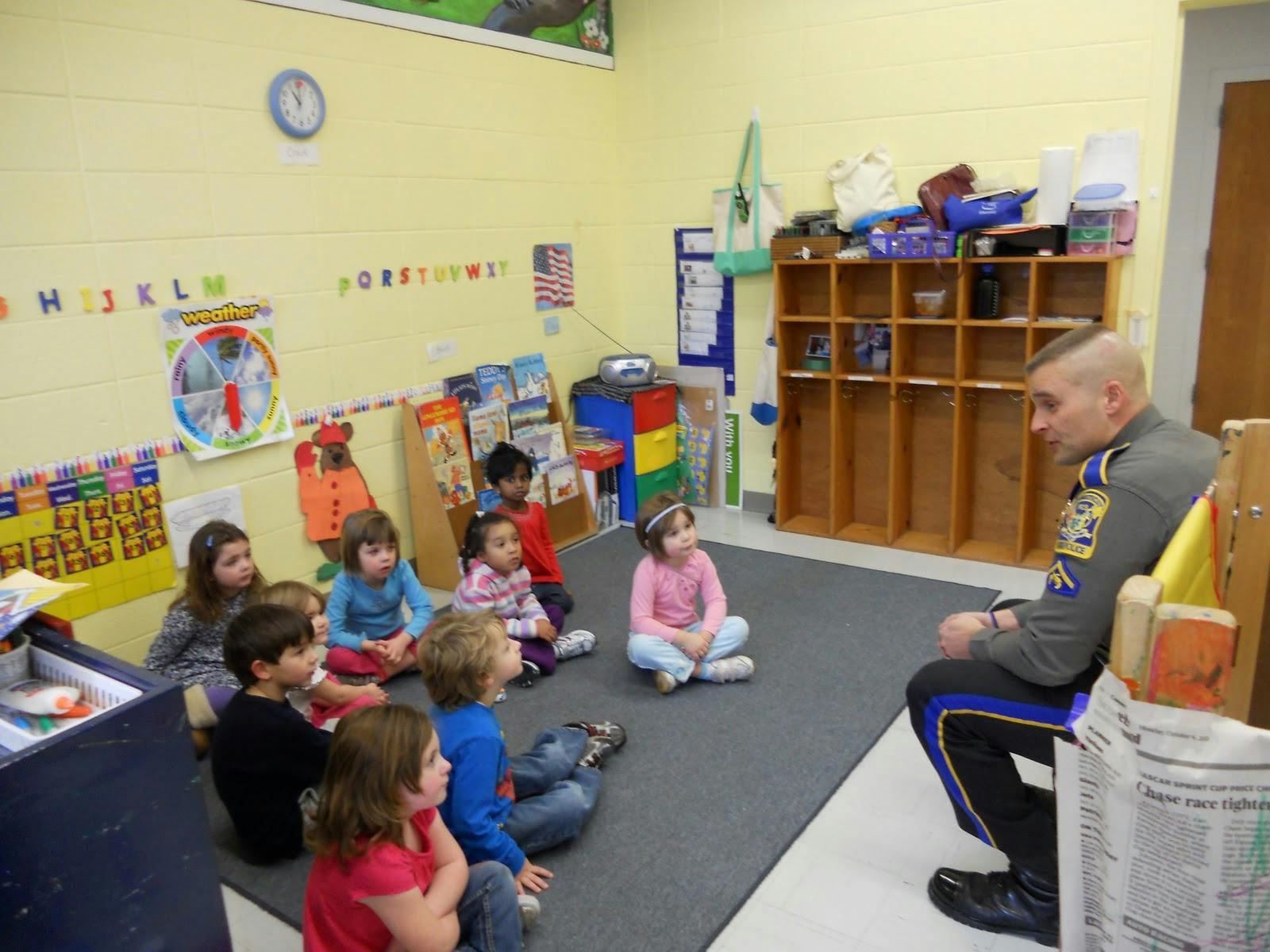 Adult in uniform speaking to a group of children sitting on the floor