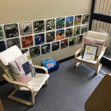 Two small chairs in a classroom with alphabet posters on the wall