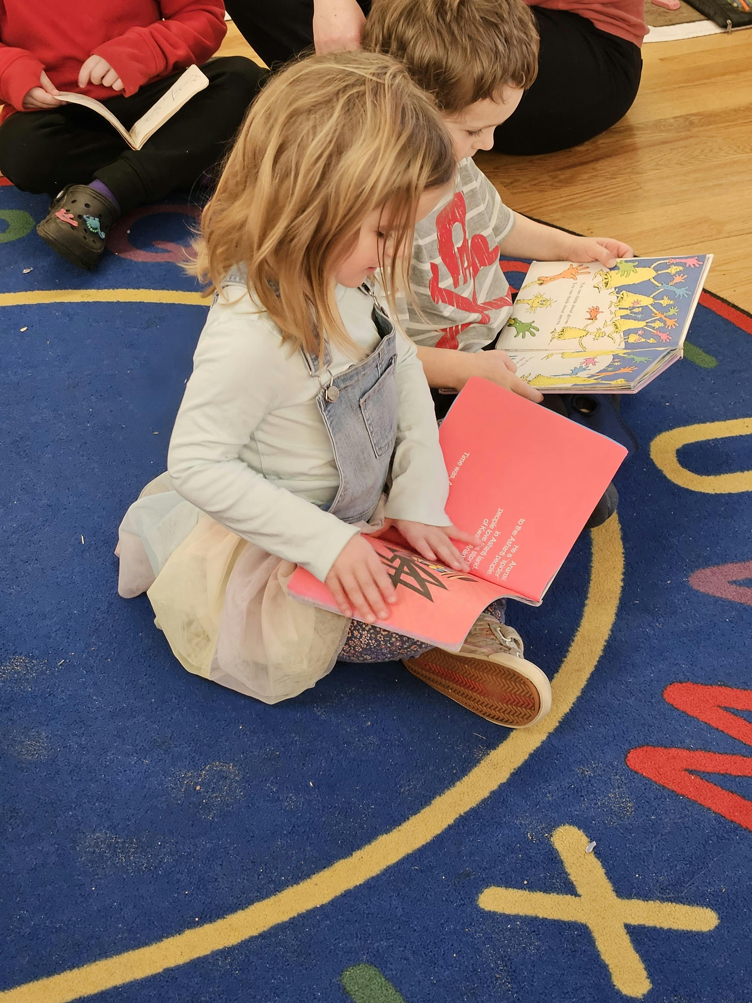 Child sitting on a rug, looking at a book