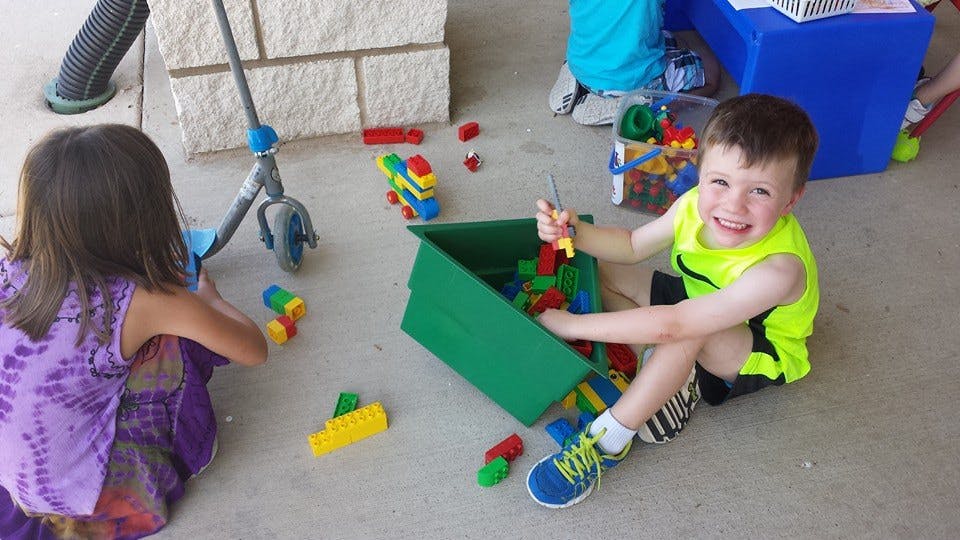 Two children playing with building blocks on the ground