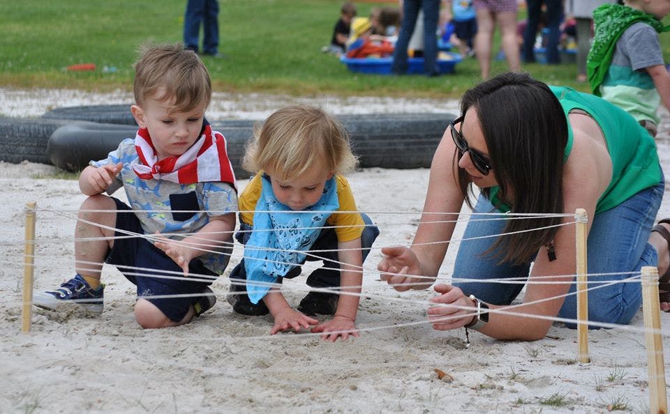 Adult and two children interacting with string maze