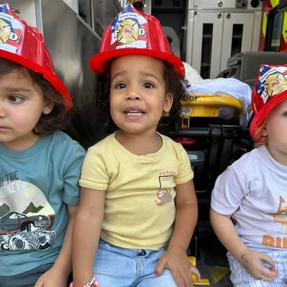 Three children wearing red firefighter hats