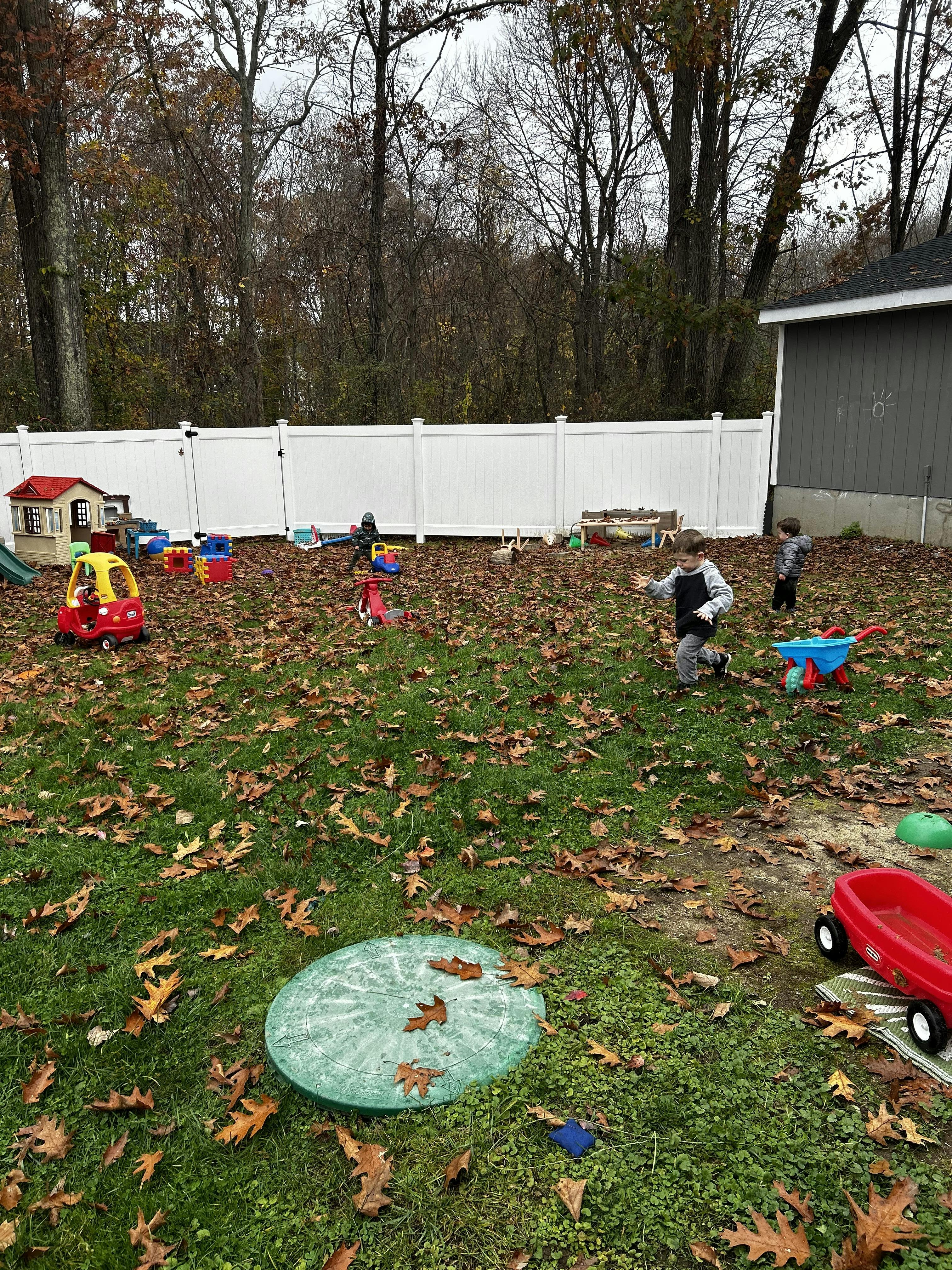 Children playing in a yard with toys and fallen leaves