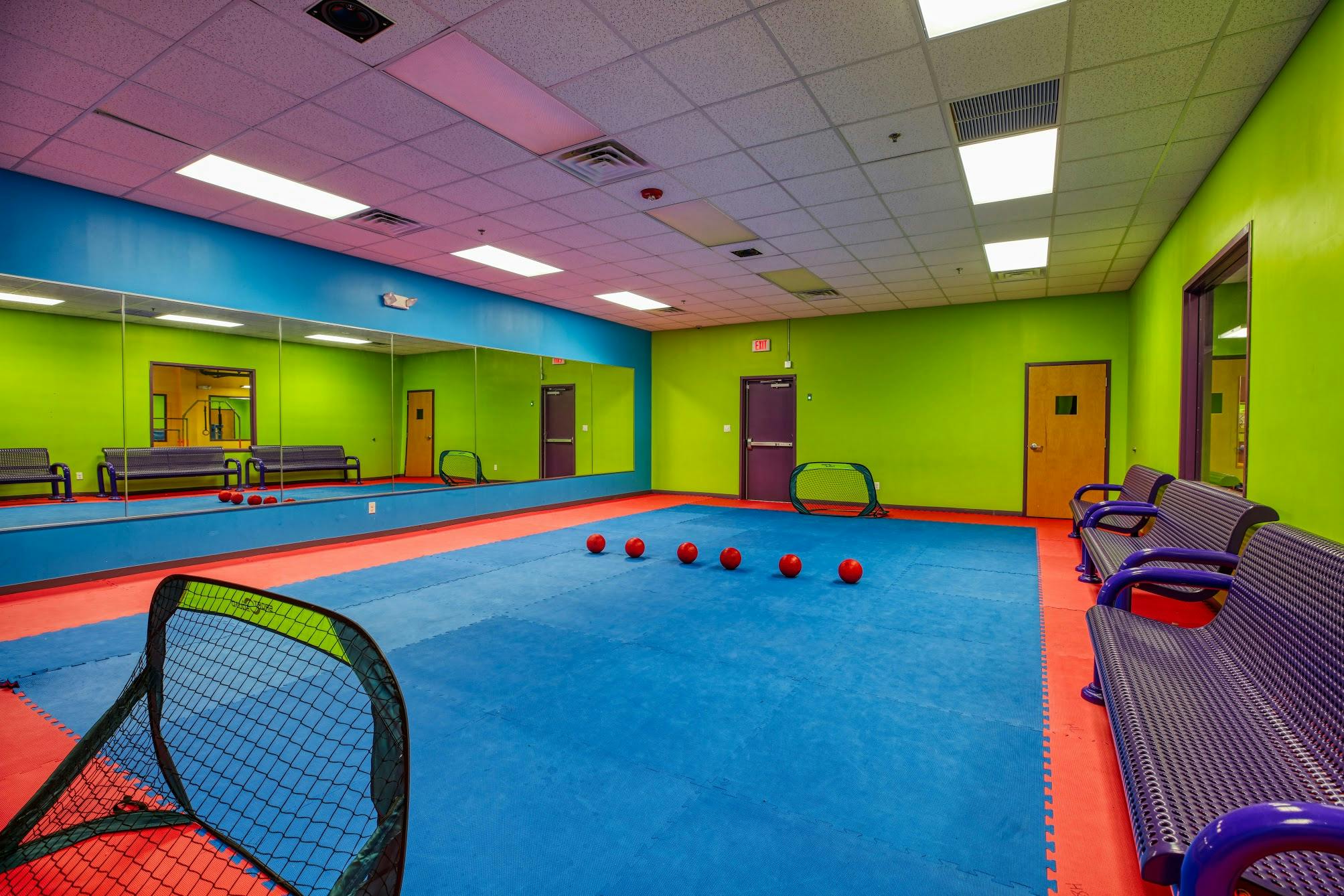 Indoor play area with blue floor, green walls, mirrors, and red balls