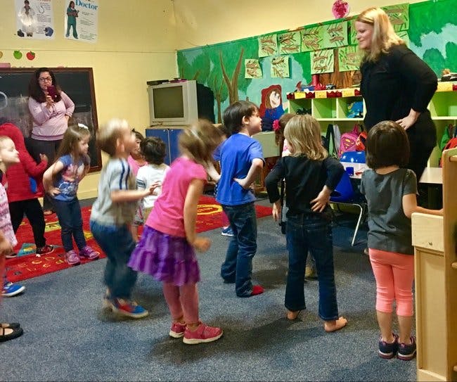 Adults and children standing in a classroom