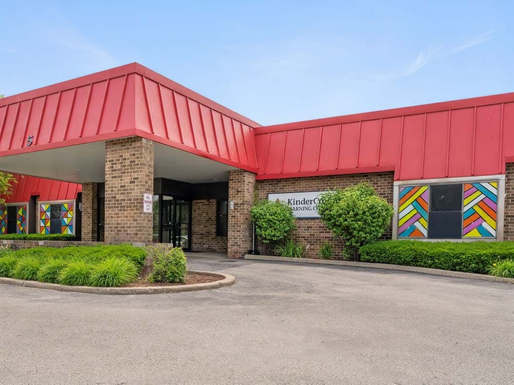Building with red roof, brick facade, and "KinderCare Learning Center" sign