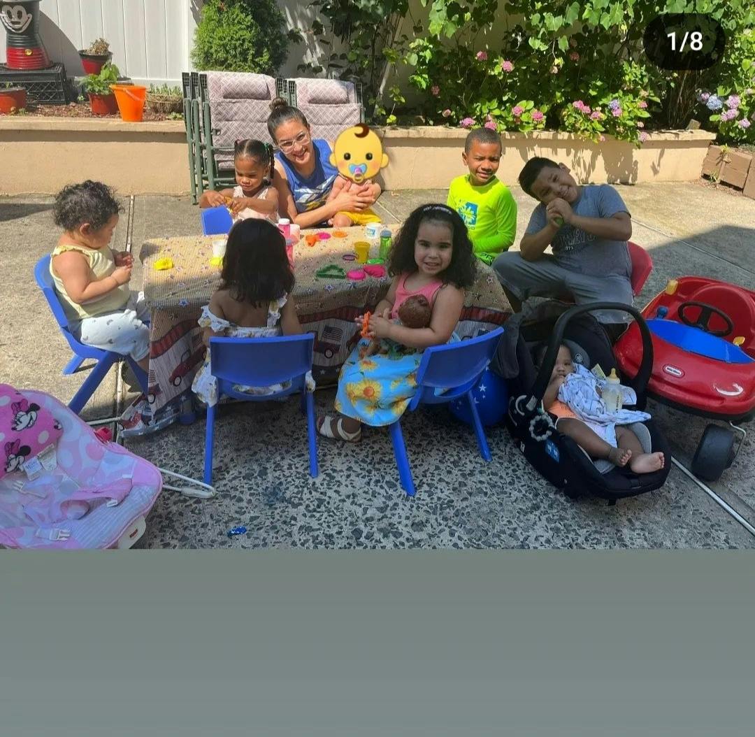 Adults and children gathered around a table outdoors