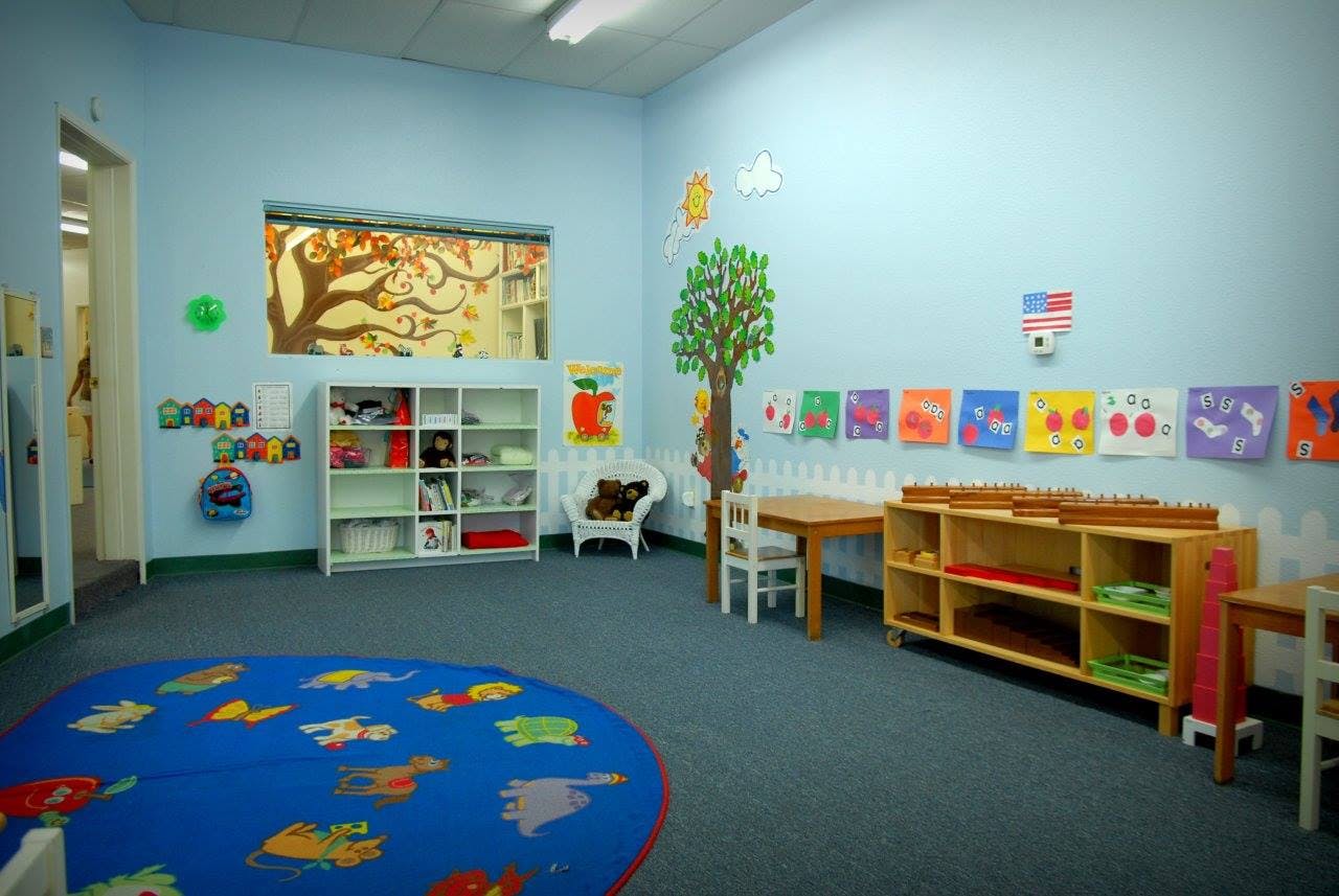 Classroom with blue walls, a blue rug, and small tables and chairs