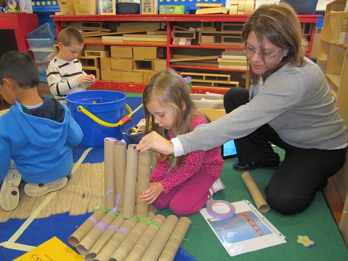 Adult and child building with cardboard tubes in a classroom