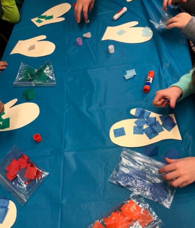 People decorating paper mittens with colorful squares