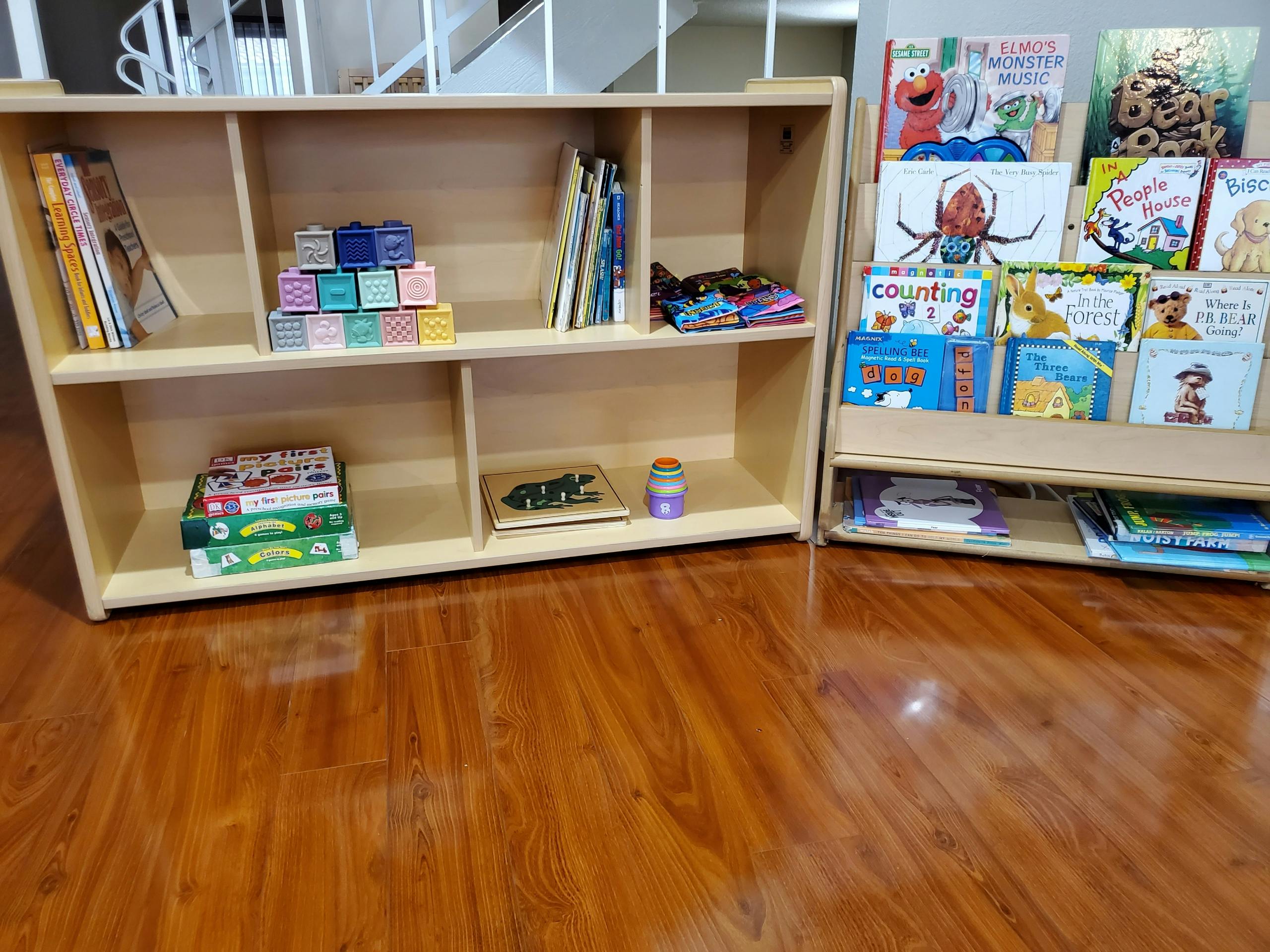 Two wooden bookshelves with books and toys