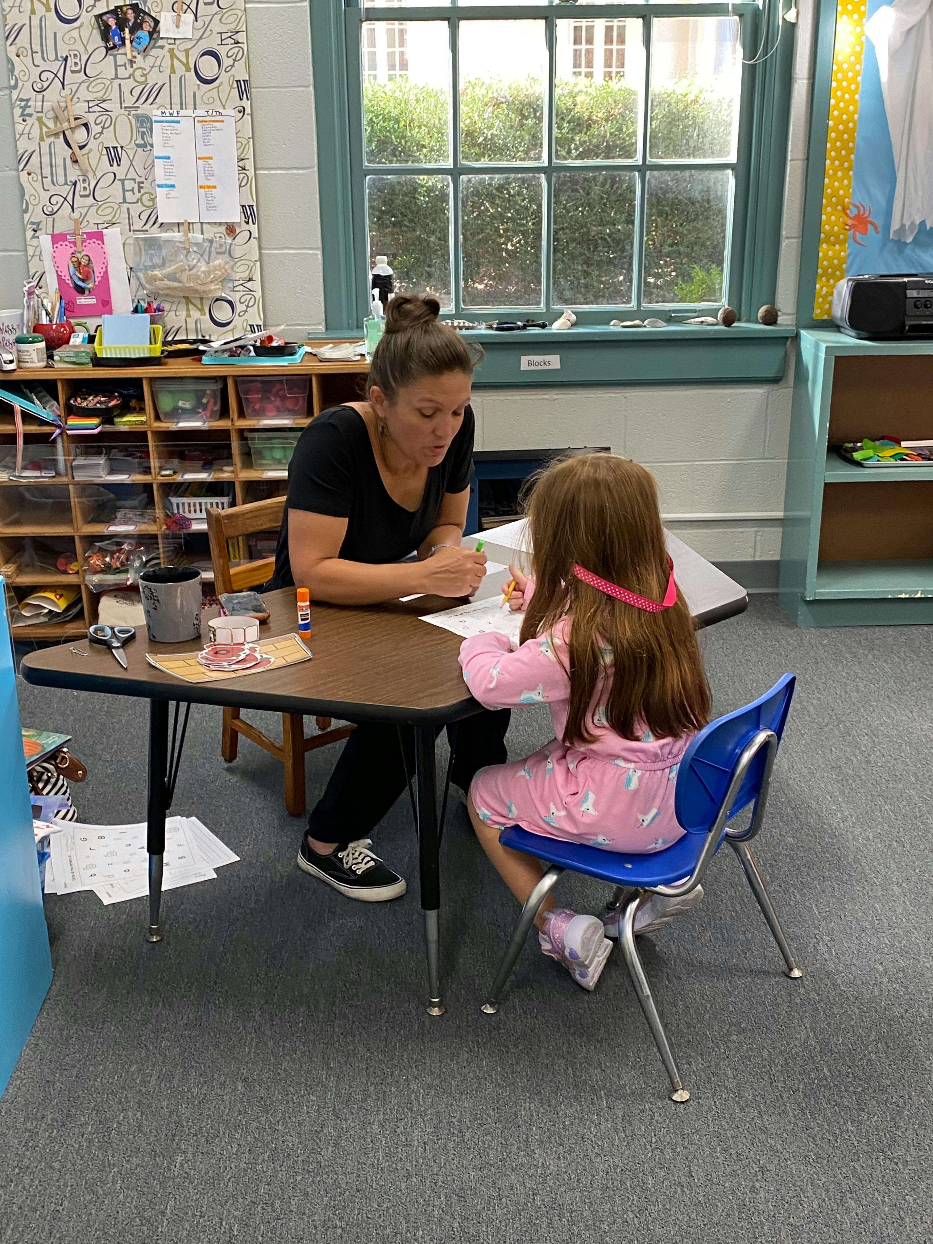 Adult and child sitting at a table, writing