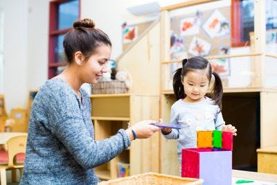 Adult and child playing with colorful blocks in a classroom