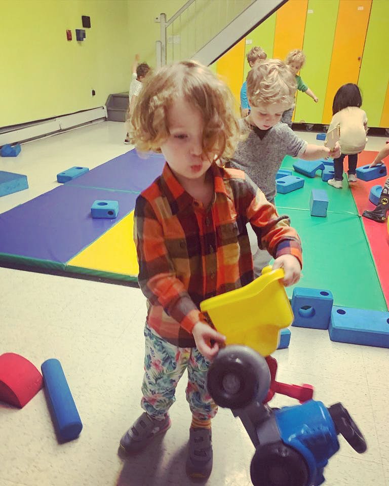 Child playing with a toy truck and yellow bucket in a play area