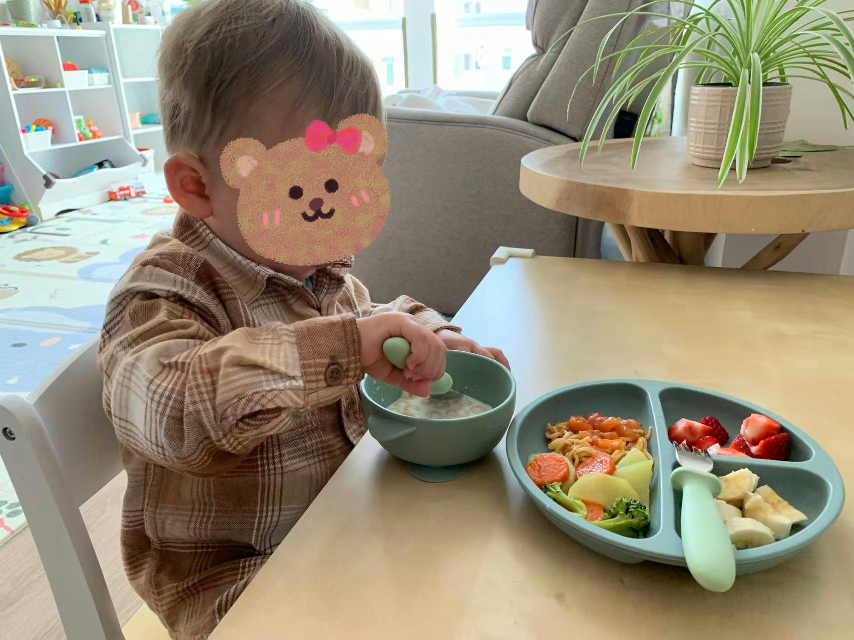 Child eating from a bowl with a spoon at a table