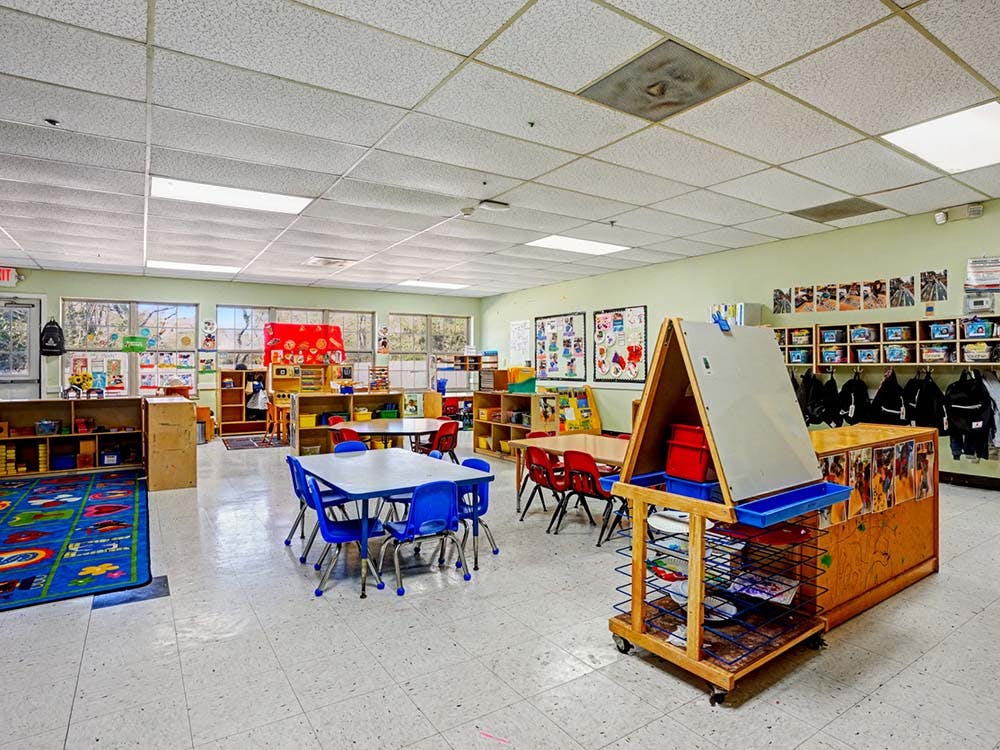 Empty preschool classroom with small tables and chairs