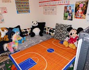 Stuffed animals on a bed with a basketball court-themed blanket