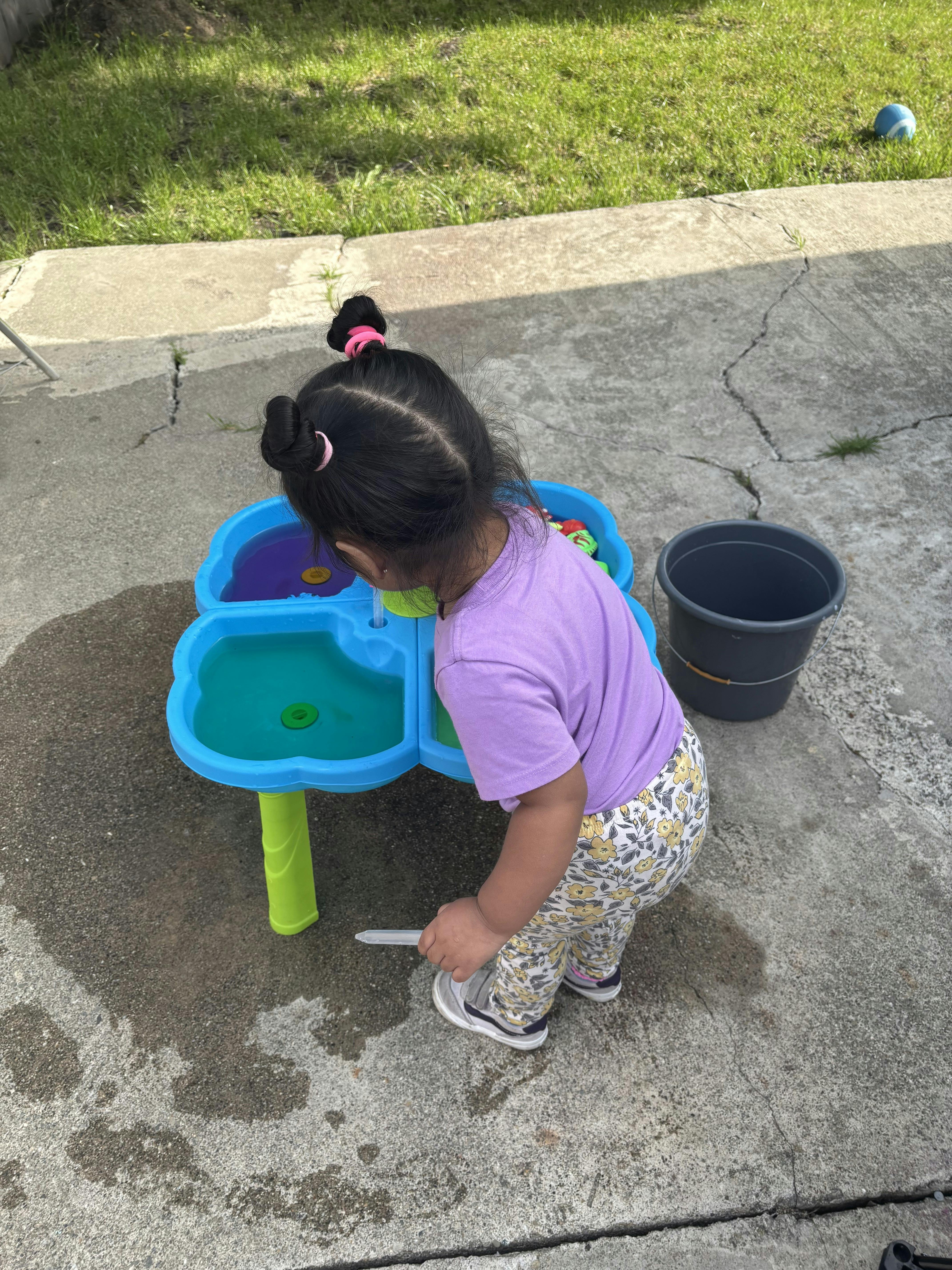 Child playing with a blue water table outside