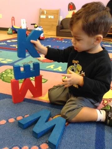 Child playing with large letter blocks on a rug